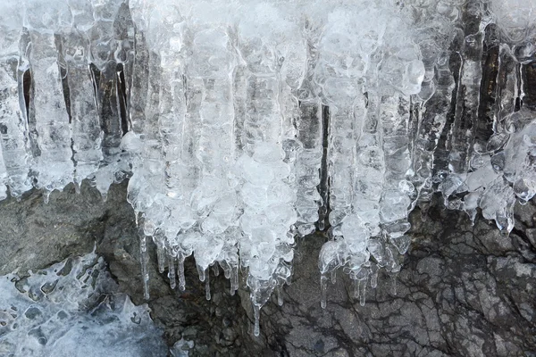 Eiszapfen auf Steinen am auftauenden Fluss im Frühling — Stockfoto