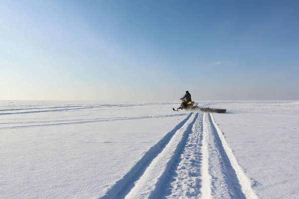 De persoon gaat op een sneeuwscooter op de bevroren rivier in de wint — Stockfoto