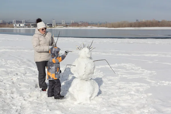 여자와 어린 소년 눈사람을 구축 — 스톡 사진
