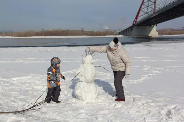 여자와 어린 소년 눈사람을 구축 — 스톡 사진