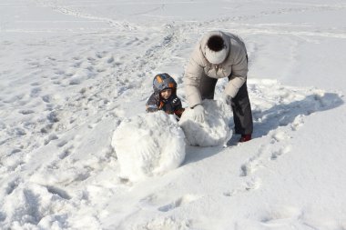 Hafif bir ceket ve küçük çocuk bir kartopu yapıyor kadın 