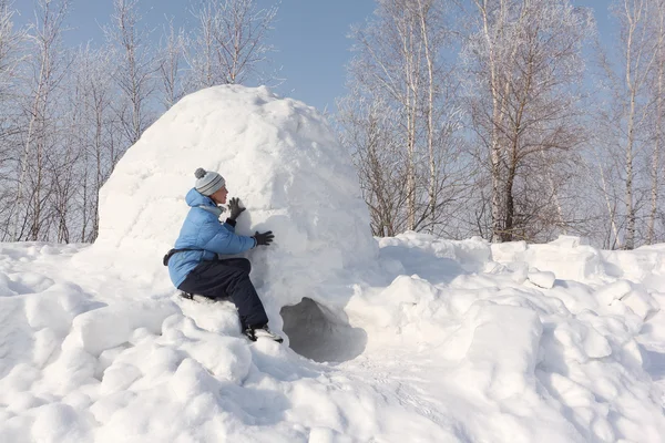 The woman in a blue jacket building an igloo on a snow glade — Stock Photo, Image