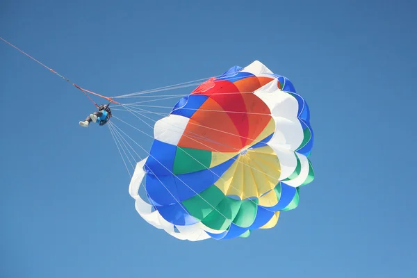 The person with a parachute on a cable flying in the blue sky — Stock Photo, Image