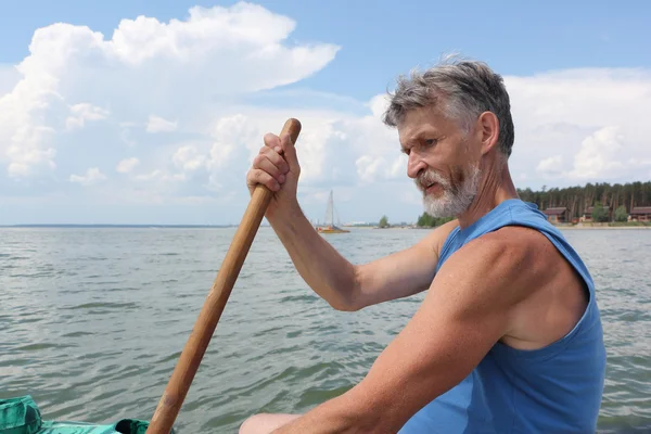 Мужчина с бородой гребёт с веслом на реке — стоковое фото