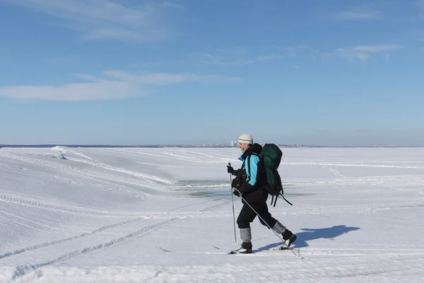 Ten człowiek podróżnik z plecakiem na nartach po śniegu rzeki — Zdjęcie stockowe