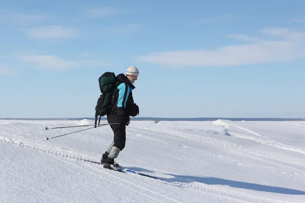 Ten człowiek podróżnik z plecakiem na nartach po śniegu rzeki — Zdjęcie stockowe