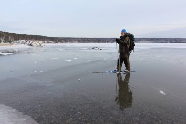 Sırt çantalı bir adam donmuş nehrin buzunda kayak yapıyor, Ob Reservoir, Novosibirsk, Rusya