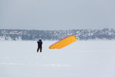 Kışın donmuş bir nehirde uçurtma eğitimi alan bir adam, Kama Reservoir, Perm City, Rusya