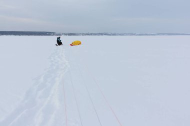 Kışın donmuş bir nehirde uçurtma eğitimi alan bir adam, Kama Reservoir, Perm City, Rusya