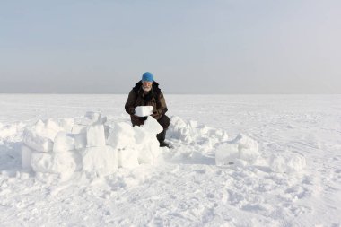 Kışın kar yığınlarından eskimo evi inşa eden adam, Ob rezervuarı, Novosibirsk, Rusya