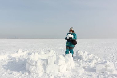 Yeşil ceketli mutlu kadın kışın karın üzerine iglo inşa ediyor, Ob deposu, Novosibirsk, Rusya