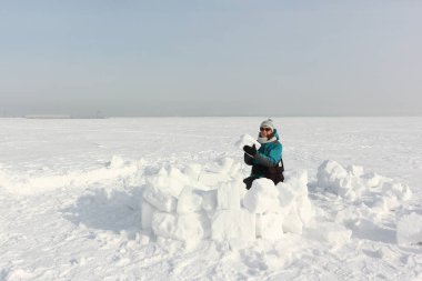 Yeşil ceketli mutlu kadın kışın karın üzerine iglo inşa ediyor, Ob deposu, Novosibirsk, Rusya