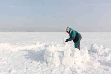 Yeşil ceketli mutlu kadın kışın karın üzerine iglo inşa ediyor, Ob deposu, Novosibirsk, Rusya