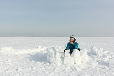Yeşil ceketli mutlu kadın kışın kara iglo yapıyor, Novosibirsk, Rusya