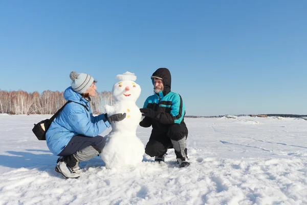 Der Mann und die Frau bauen einen Schneemann — Stockfoto