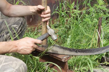Adam bir çekiç bir bahçe tırpan yener