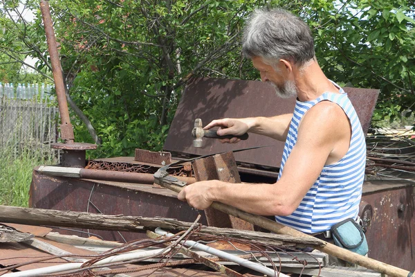 The man beats off scythe a hammer in a garden — Stock Photo, Image