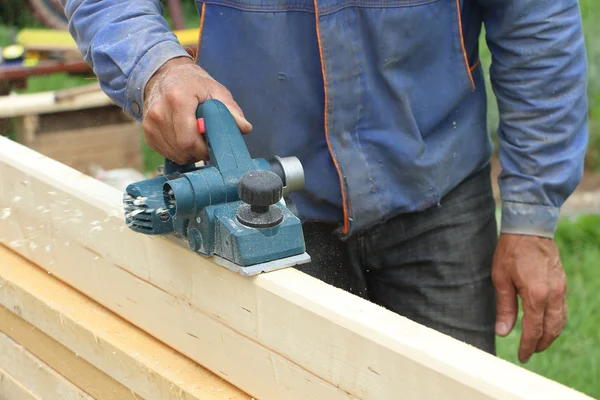De mannelijke hand verwerkt een houten plank een elektrische jointer vliegtuig — Stockfoto