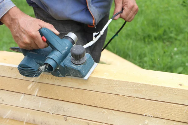 The male hand processes a wooden board an electric jointer plane — Stock Photo, Image