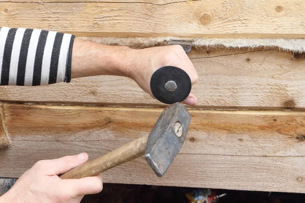 Male hands caulk a house wall from a bar — Stock Photo, Image