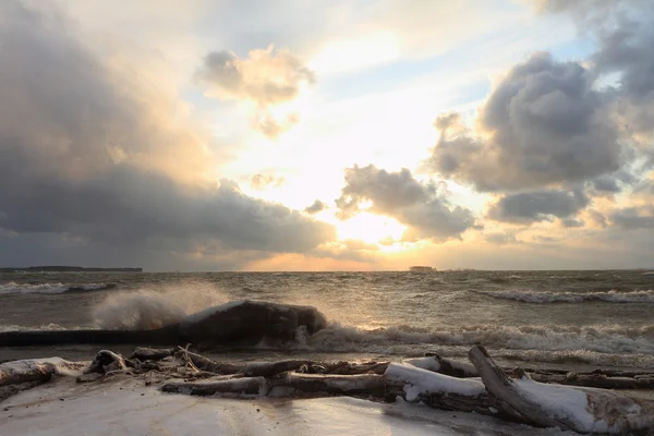 Die fließenden Wellen an der sandigen, schneebedeckten Küste auf einem Stausee — Stockfoto