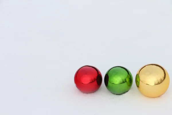 Glass color spheres lying in snow outdoors — Stock Photo, Image