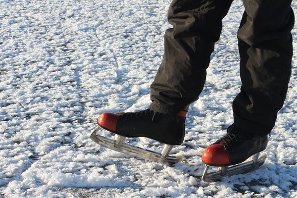 Pieds masculins dans les patins sur une surface enneigée de la rivière — Photo