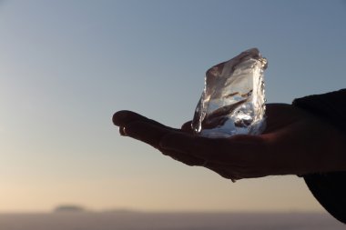 Buz kristal günbatımı gökyüzüne karşı bir erkek elinde