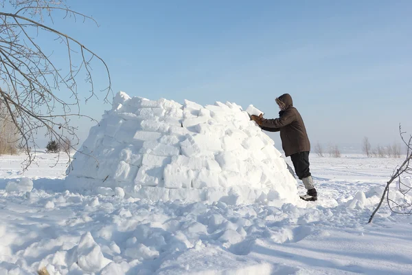 男子在冬天建立在雪林间空地上的一座冰屋 — 图库照片