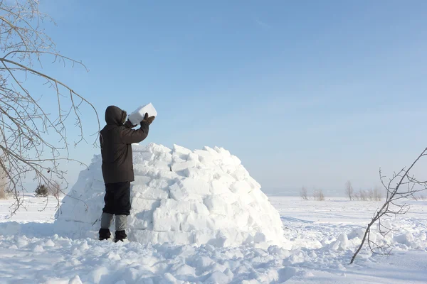 男子在冬天建立在雪林间空地上的一座冰屋 — 图库照片