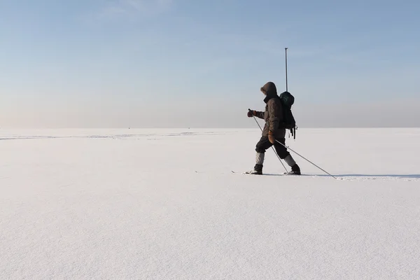 Человек путешественник с рюкзаком катается на лыжах по снегу реки — стоковое фото
