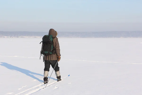 Der Mann der Reisende mit dem Rucksack, der auf dem Schnee des Flusses Ski fährt — Stockfoto