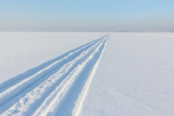 Rastros de una moto de nieve en una superficie de nieve del río —  Fotos de Stock