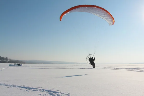 The person flying on a motorized paraplane against the snow — Stock Photo, Image