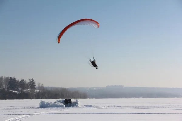 De persoon die vliegen op een gemotoriseerde paraplane tegen de sneeuw — Stockfoto