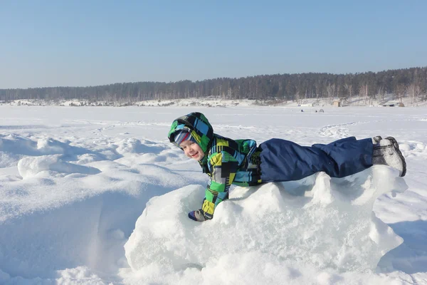 Le petit garçon dans une veste de couleur couché sur un bloc de glace dans le wi — Photo