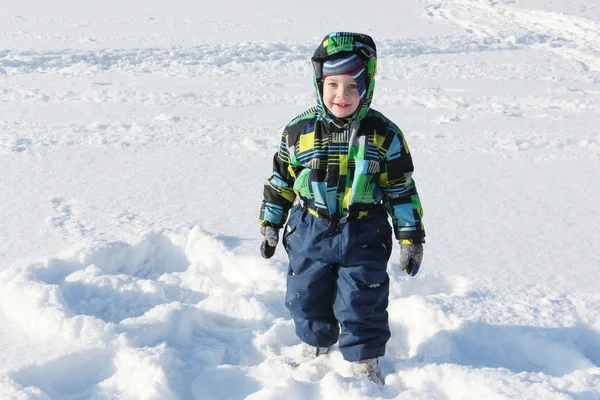 Portret van de kleine jongen in een kleur jas tegen sneeuw in de winter — Stockfoto