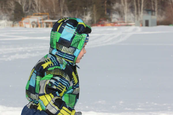 Il bambino in una giacca a colori che corre su neve nell'inverno — Foto Stock