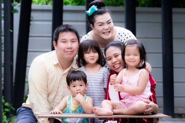 Büyük ailenin tatilde birlikte zaman geçirmesi kavramı. İki aile anılarını filme çekerken eğlendi. Çocuk parmağını emdi. Yazın veya ilkbaharda tatlı bir gülümseme. İki kız tatlı tatlı gülümsüyor. Ebeveynler çocuklarını kucaklıyor..