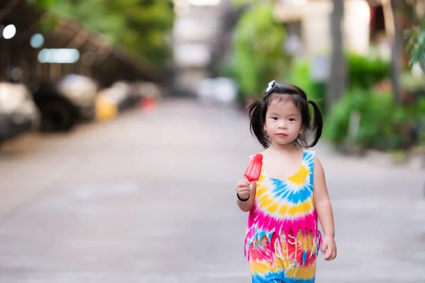 Gadis Kecil Berambut Hitam Berdiri Memegang Loli Merah Dan Tersenyum — Stok Foto