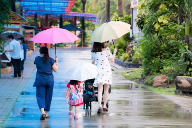 Bangkok Tayland - 19 Sep 2020. Aile yağmur mevsiminde yağmur çiselemesinde yürüdü ve şemsiye tutuyordu. Sağlık hizmetleri. İnsanların arkası şemsiyelerle yürüyordu..
