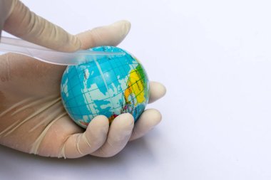 Plastik bıçağı tutan kişinin eli mavi plastik küreyi kesiyormuş gibi yapıyor. Küresel ısınma kampanyası kavramı. İzolasyon beyaz arka planda.