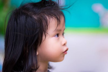 Asyalı şirin küçük kızın portresi. Evde meraklı bir yüzü var. Aktif bir çocuk, önünde ilginç şeylerle yukarı bakıyor. Ağzında biraz leke vardı. Çocuk öğrenir ve konsept oynar.