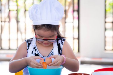 Asyalı kız yemek yapmayı ya da atıştırmayı öğreniyor. Gözlüklü çocuk yumurtayı mavi-beyaz kaseye sokuyor. Yumurta büyük bir kaseye düşmek üzereyken çocuk heyecanlanıyor. Tatlı çocuk 6 yaşında.