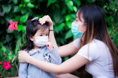 Anne, Covid-19 virüsü salgınında maske takmasının nedenini açıklamak için kızıyla konuşmaya çalıştı. Anne ve çocuk tıbbi maske takıyor. Zatürreeden kendini koruma kavramı.