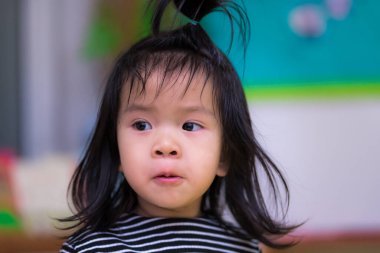Asyalı suratını asıyor, siyah saçlı çocuk. Çocuk siyah beyaz çizgili bir gömlek giyiyordu. Şirin çocuk yan taraftan bir şeye bakıyor. 3 yaşındaki bir çocuğun gizli fotoğrafı..