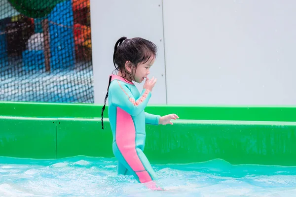 亚洲小孩穿着薄荷绿色泳衣的侧视图 孩子们在玩滑水游戏后 正在用水擦拭她的脸 和家人一起在水上公园度假 3岁半的孩子在湿透的水里玩耍 — 图库照片