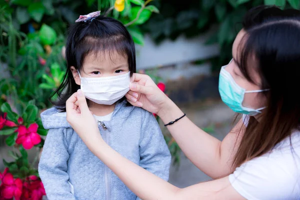 Family and child girl wear medical face masks outside the home or park. Mother and daughter wearing mask during flu coronavirus outbreak and PM 2.5. Prevention of infection from viruses and dust smoke