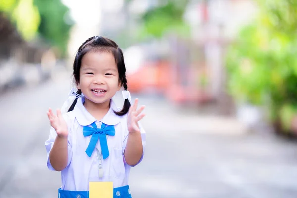 青と白の学校の制服を着て幼稚園の学生は スタンディングオベーション 学校に行くことを嬉しく思います 学期開始日の朝の甘い笑顔 両側にアジアの子供ニット編組 — ストック写真