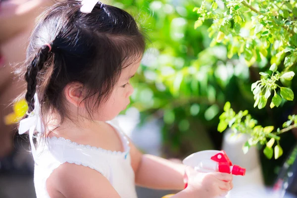 愛らしいアジアの少女は 家の前の木の世話をします かわいい子供は植物のスプレーを引き裂く 家事の手伝いをする子どもたちのコンセプト放課後 家庭支援研修 — ストック写真
